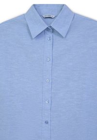 Camicia button-up azzurro chiaro realizzata in tessuto morbido, con colletto classico, sette bottoni sul davanti e una leggera texture.