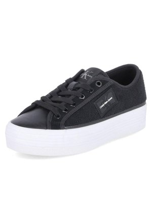 Sneaker noir avec un dessus texturé en tissu noir et cuir, doté d'une semelle plateforme blanche, de lacets noirs et d'une étiquette de logo sur le côté.