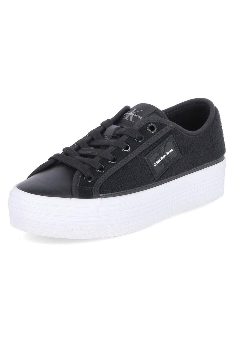 Sneaker noir avec un dessus texturé en tissu noir et cuir, doté d'une semelle plateforme blanche, de lacets noirs et d'une étiquette de logo sur le côté.