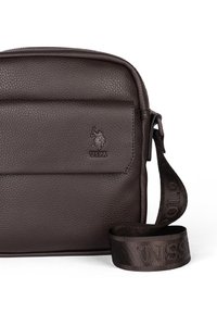 Hnědá kožená crossbody taška s texturovaným povrchem, s embosovaným logem USPA na přední straně a nastavitelným popruhem s brandingovým detailem.