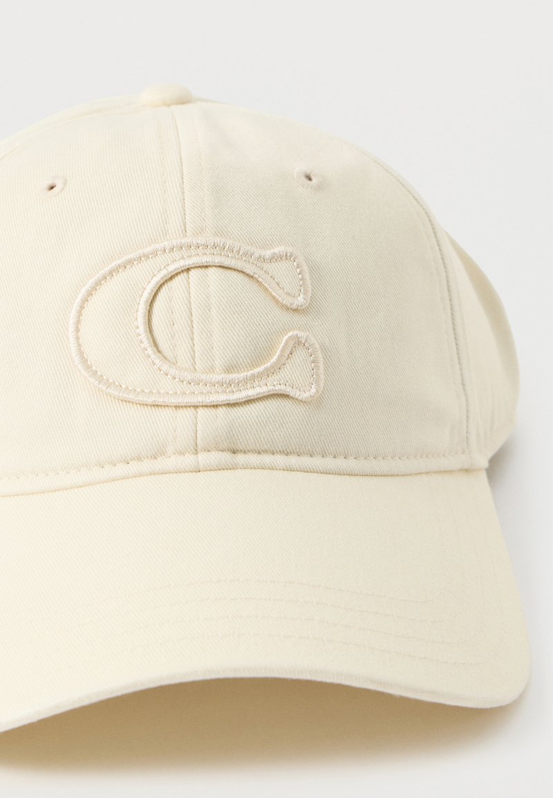 Beige Baseballmütze aus Baumwolle mit einem auffälligen gestickten Buchstaben "C" auf der Vorderseite. Glatte Textur mit sechsteiligem Design.