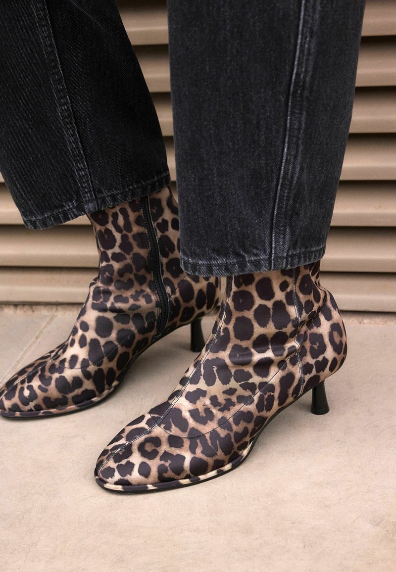 Stivaletti alla caviglia in stampa leopardata con un design elegante, punta appuntita e tacco a stiletto piccolo. Realizzati in tessuto liscio con dettagli di zip laterale.