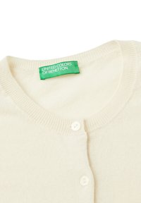 Kremowy sweter z dzianiny z okrągłym dekoltem, zapięciem na guziki i zieloną metką z napisem "UNITED COLORS OF BENETTON."