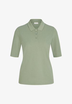 Polo shirt vert olive avec col et trois boutons, associé à un pantalon large beige clair. Des baskets blanches complètent la tenue.