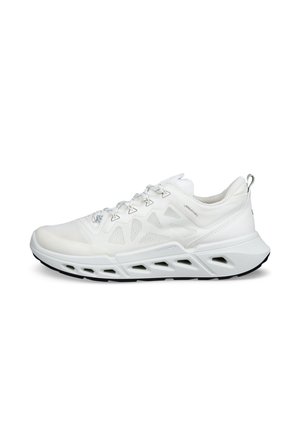 Zapatilla de running blanca de malla, con cordones blancos, una suela gruesa y esculpida y la banda de rodadura negra, mostrada de perfil sobre un fondo blanco.