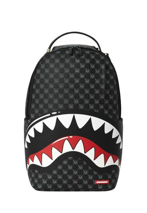 Mochila negra con un patrón a cuadros y un gran gráfico de afilados dientes de tiburón blancos y rojos en el bolsillo delantero.