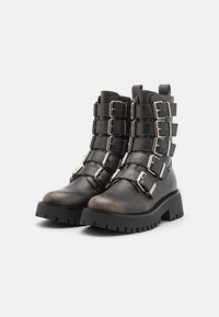 Botine negre din piele cu mai multe catarame argintii, talpă groasă neagră și finisaj texturat, având un design robust.