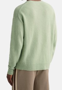 Maglione a maglia verde chiaro con vestibilità rilassata, orlo a coste e maniche raglan, realizzato in un morbido tessuto testurizzato.