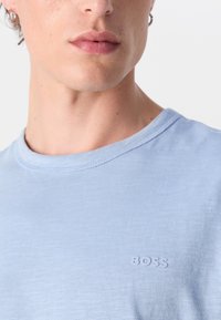 Camiseta de mangas curtas azul claro em algodão macio e texturizado, com um logótipo "BOSS" em relevo no peito e um clássico decote redondo.