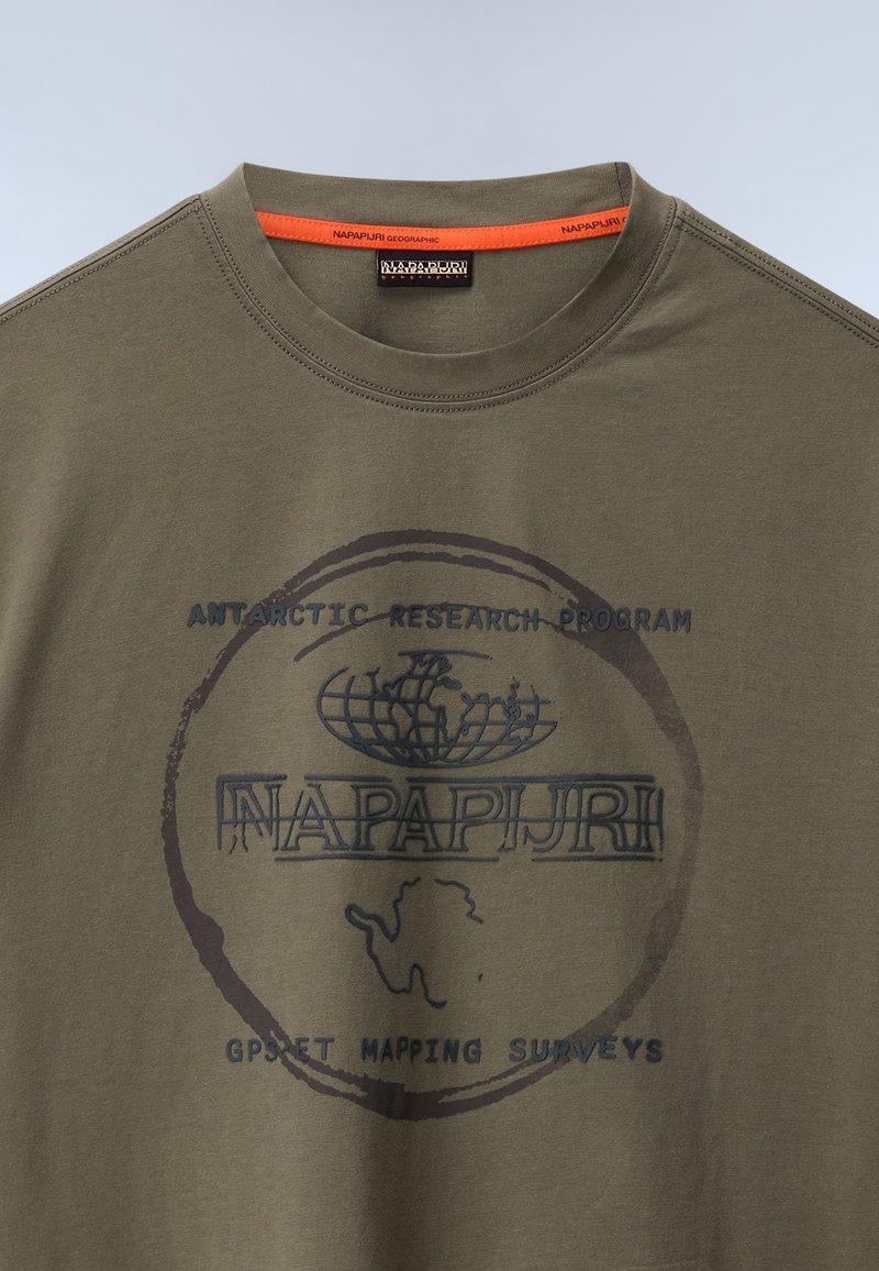 Koszulka z krótkim rękawem w oliwkowym kolorze z bawełny, z okrągłą grafiką w kolorze granatowym oraz tekstem związanym z badaniami i mapowaniem Antarktydy.