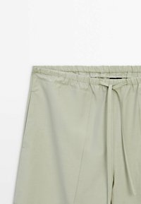 Shorts vert clair avec taille élastique, poches avant et fermeture à cordon, affichés sur fond blanc.
