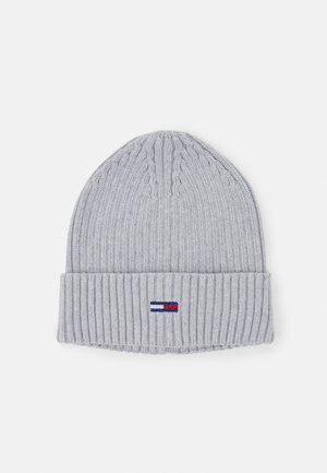 Bonnet en tricot côtelé gris clair avec revers et petite étiquette rectangulaire rouge, blanche et bleue centrée à l’avant.