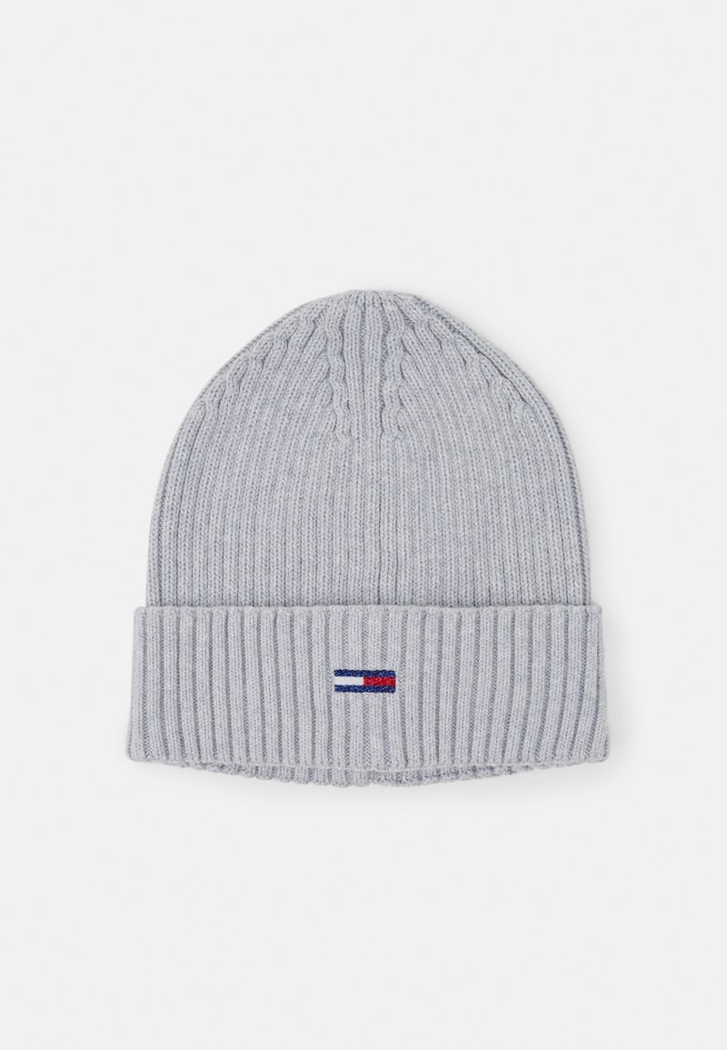 Bonnet en tricot côtelé gris clair avec revers et petite étiquette rectangulaire rouge, blanche et bleue centrée à l’avant.
