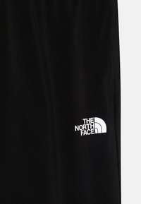 Črne atletske kratke hlače iz gladkega materiala, s belim logotipom "The North Face" na spodnji levi strani.