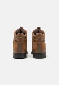 Stivaletti alla caviglia in pelle scamosciata e pelle marrone con colletto imbottito, con dettaglio logo verde e suola in gomma nera. Linguetta posteriore per una facile calzata.