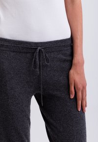 Donkergrijze sweatpants gemaakt van zacht materiaal met een trekkoord in de taille, met een relaxte pasvorm en subtiele textuurdetails.
