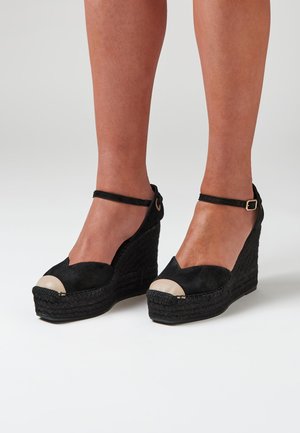 Zwarte suède wedge-sandalen met een geweven jute basis, open teen en een contrasterende crèmekleurige neus. Voorzien van een enkelbandje met een gouden gesp.