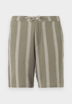 Calções verdes de tecido texturizado, com riscas brancas verticais, uma cintura com cordão ajustável e bolsos laterais angulados.