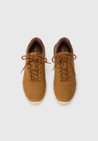 Brown suede sneakers with round toe, perforated design, lace-up front, and contrasting brown laces. Lightweight white sole and padded collar.