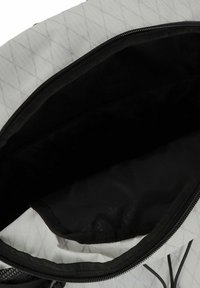 Borsa in tessuto grigio trapuntato con interno nero, caratterizzata da un'apertura con zip e accenti texturizzati neri lungo i bordi.