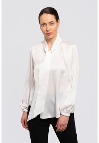 Weißes Satinbluse mit langen Ärmeln, gerafftem Ausschnitt und einer Frontbindedetail. Glatte Textur mit lockerem Schnitt. Kombiniert mit schwarzen Hosen.