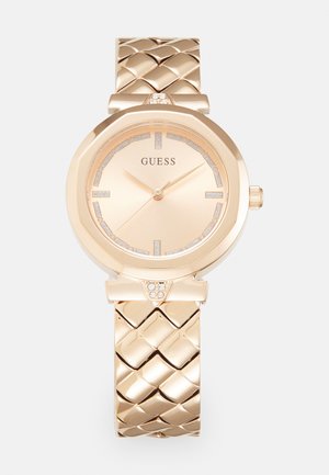 Złoty zegarek z teksturowanym, plecionym paskiem. Okrąła tarcza z różowozłotym cyferblatem i kryształowymi akcentami na znacznikach godzin oraz koronie.