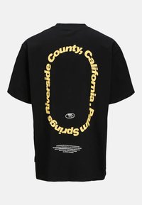 Camiseta de algodón negra con texto amarillo en negrita en un diseño circular, que detalla "Riverside County, California, Palm Springs."