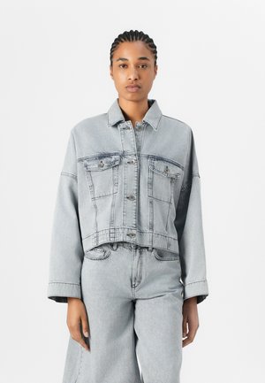 Kuttet grå denimjakke med lange ermer, to brystlommer og knappelukking, med en lett falmet tekstur.