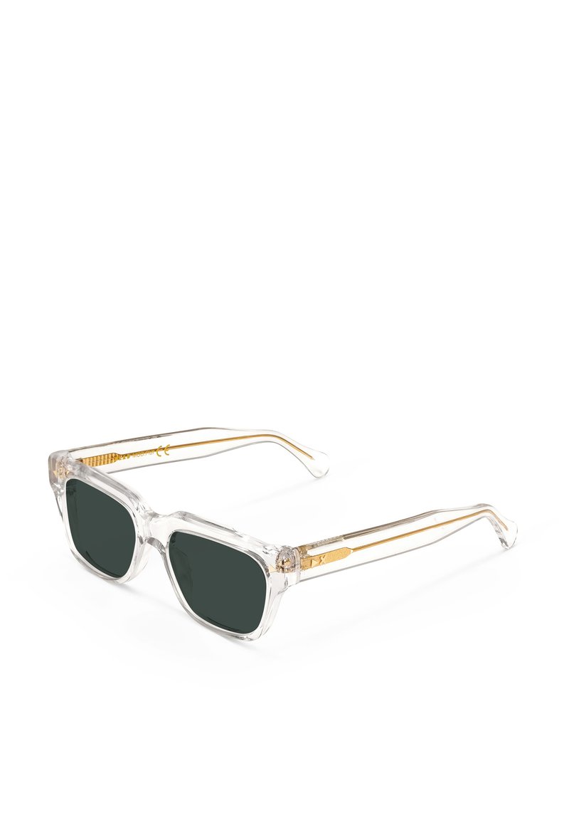 Occhiali da sole con montatura trasparente e lenti verde scuro; tempietti con accenti dorati e un design testurizzato. Struttura robusta con forma angolare.