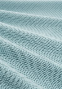 Světle modrá pletenina s žebrovanou strukturou a horizontálními vlnami, které vytvářejí stíny a hloubku.