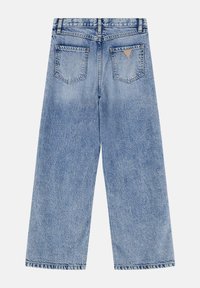 Jean large en denim bleu clair à taille haute, avec des poches arrière et une petite étiquette triangulaire. Texture délavée sur l'ensemble.