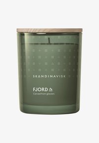 Grøn glas lysestage med indtagne geometriske mønstre, trælåg, der har "SKANDINAVISK" og "FJORD" brandingdetaljer.