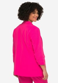 Blazer rose vif avec une coupe ajustée, des revers en pointe et des manches trois-quarts. Texturé lisse et détails de drapés subtils dans le dos.