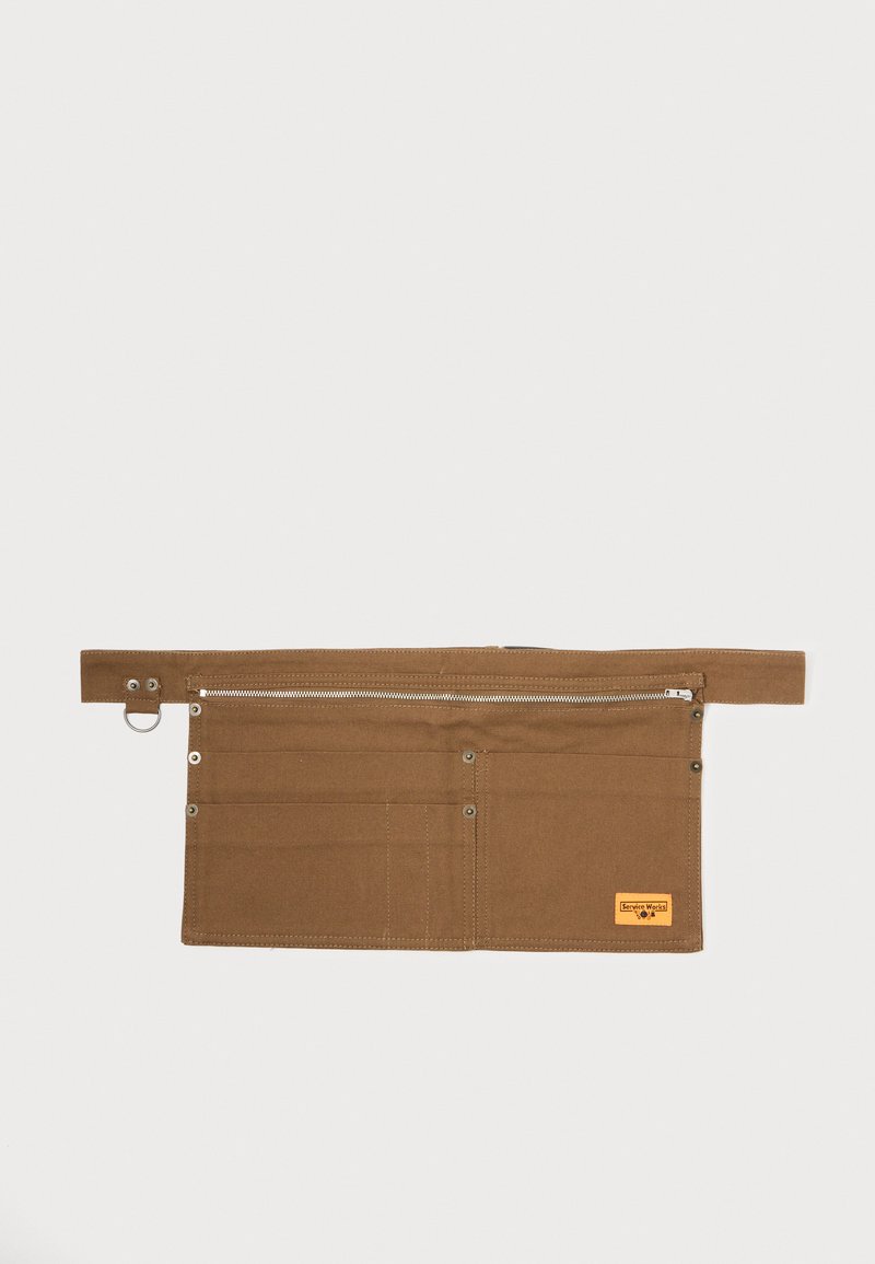 Pruun kangast tööriistavöö, millel on tõmblukuga tasku, mitu avatud taskut, metallist riistvara ja brändipatch. Lame kujundus lihtsaks ladustamiseks.