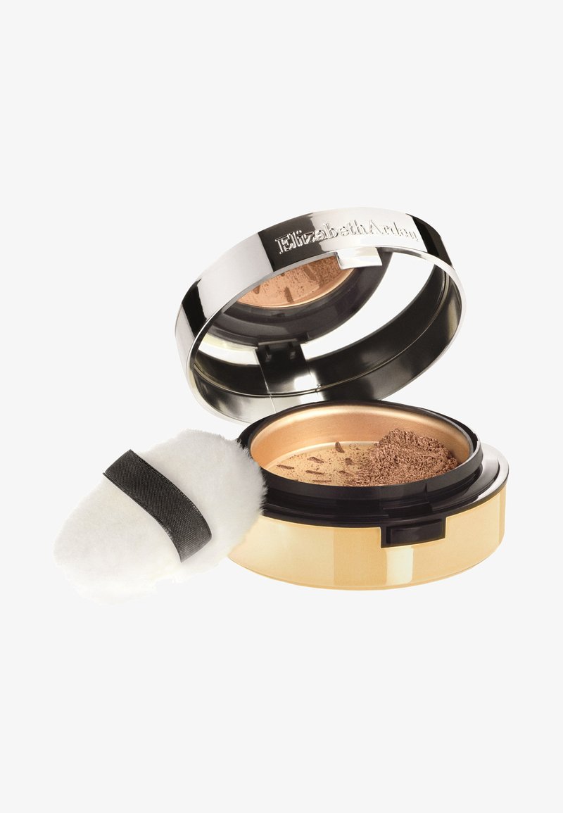 Losse poederfoundation in een ronde, metalen compact. Heeft een glanzend zilveren deksel en een gouden basis, met een zacht applicatorpad erbij.