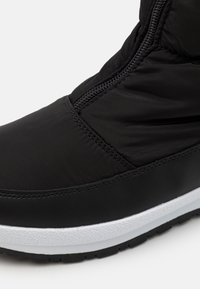 Sort polstret ankelstøvle med lynlås i siden, tekstureret stof og en hvid gummisål med mønstret greb.