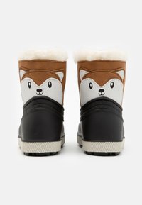 Bottes sur le thème du renard avec un dessus marron, un motif de visage blanc, une doublure en fausse fourrure douce et une section inférieure noire. Semelle en caoutchouc texturé.