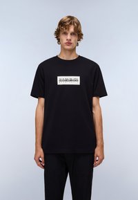 Sort bomulds T-shirt med korte ærmer, med et rektangulært grafisk print i hvid og sort, der inkluderer teksten "NAPAPIJRI geographic."