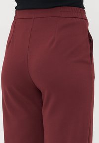 Bordørbuks med elastisk midje og jevn tekstur, har sidelommer og en skreddersydd passform, vist fra siden.