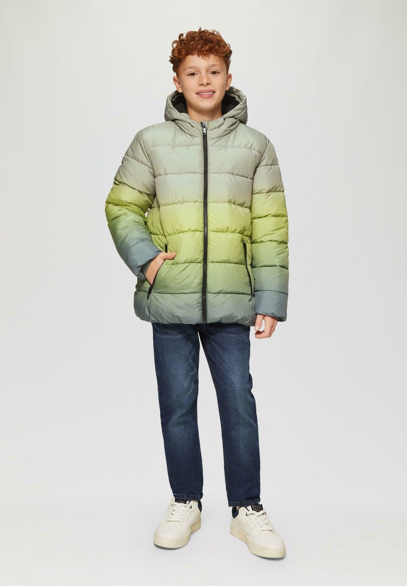 Daunenjacke in abgestuften Grün- und Grautönen, mit Reißverschluss vorne, Kapuze und seitlichen Taschen. Kombiniert mit dunklen Jeans und Sneakers.