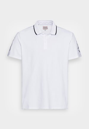 Polo blanco de algodón con un tapeta de dos botones, ribete negro en el cuello y logo impreso en las mangas. Mangas cortas y bajo recto.