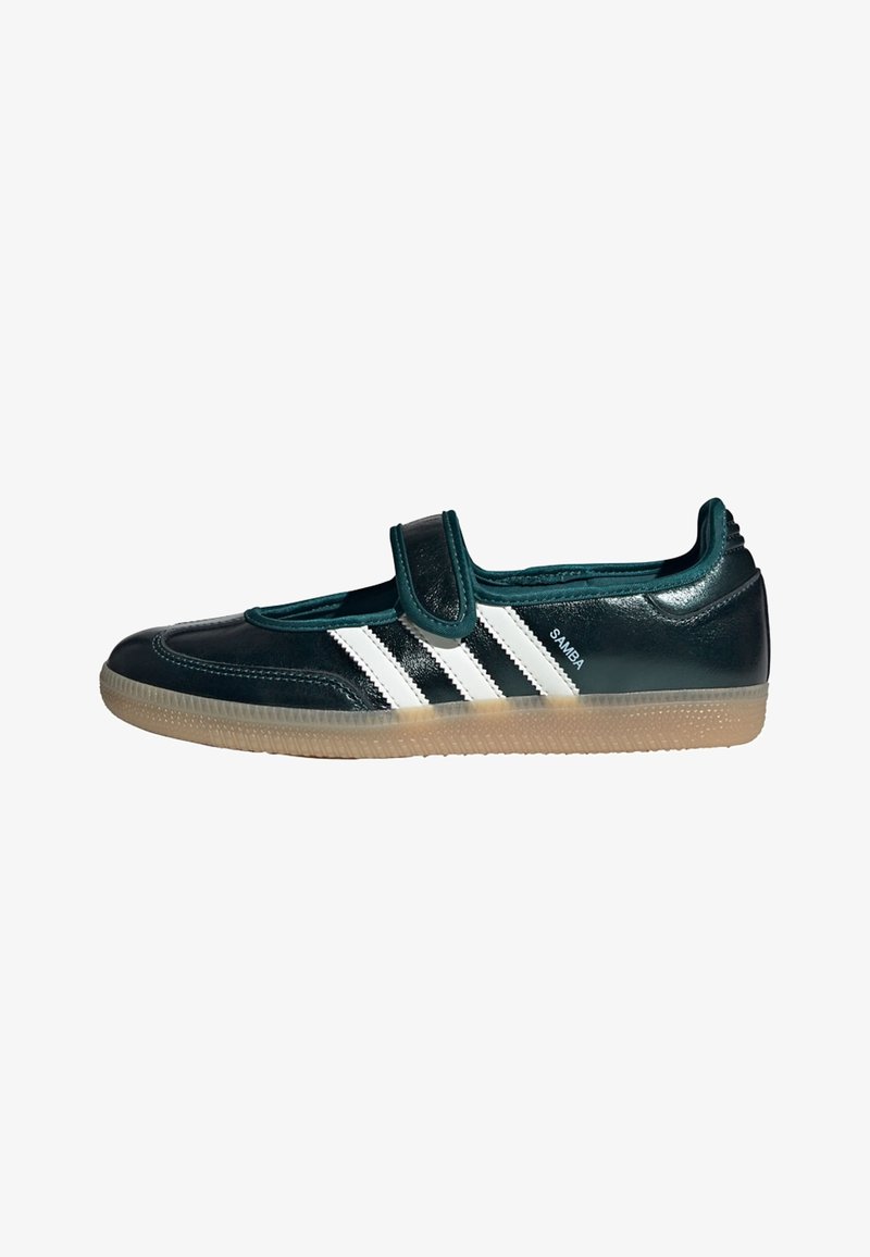 Black Adidas Samba shoe with white stripes and a Velcro strap, featuring a gum sole and low-profile design.