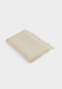 Coperta intrecciata beige con motivo a quadri, caratterizzata da bordi sfrangiati e una texture morbida. Piegata ordinatamente per la visualizzazione.