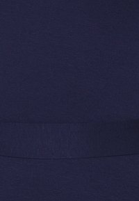 Mörkblå stretchtyg med en slät yta, försett med ett brett elastiskt band upptill, designat för komfort och lättanvändning.