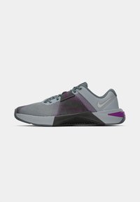 Nike sportssko med en gray mesh-overdel, lilla accenter og en struktureret sort gummi sål, designet til ydeevne og komfort.