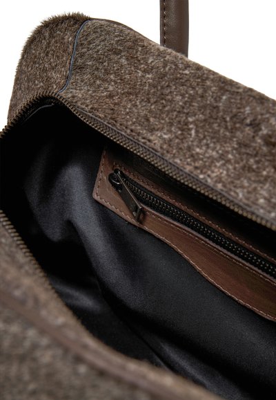 Borsa in feltro marrone con apertura con zip. L'interno presenta una foderatura nera e una piccola tasca con zip in pelle marrone. Texture morbida complessivamente.