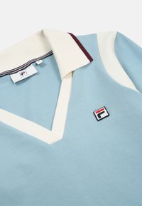 Lichtblauw poloshirt met een witte en bordeauxrode gestreepte kraag, met een v-hals ontwerp en een geborduurd logo aan de linkerkant.