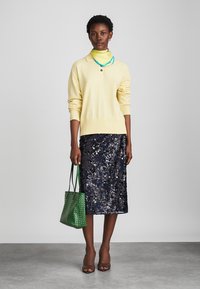 Geltonas megztas svarkas su apykakle, tamsiai mėlyna blizgučiais dekoruota sijonas, žalia raštuota rankinė, ir ruda aukštakulnių batai. Yra sluoksniuota kaklo aksesuaras.