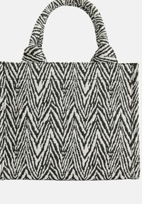 Taška přes rameno s černobílým vzorem cikcak z tkané látky, s dvěma pevnými uchy a pevně tvarovaným obdélníkovým tvarem.