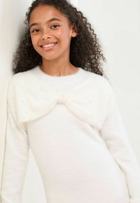 Weißer, flauschiger Pullover mit einer Schleifenverzierung am Ausschnitt, geschmückt mit kleinen dekorativen Perlen. Weicher Stoff und lange Ärmel.